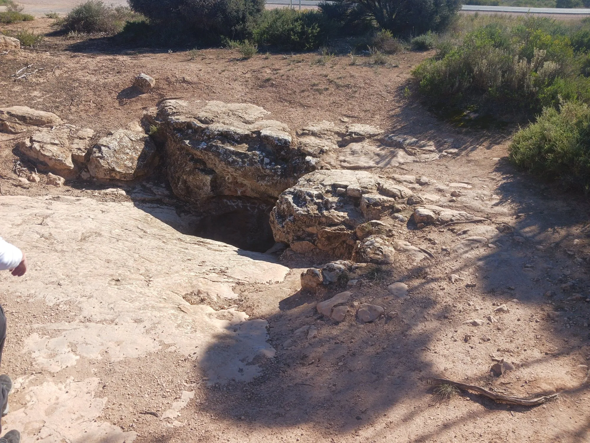 The opening of the Caiguna Blowhole in limestone rock among low scrub