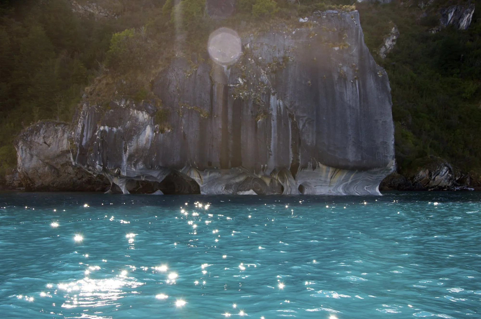 Striped marble rock formations rising from turquoise water on Lago General Carrera
