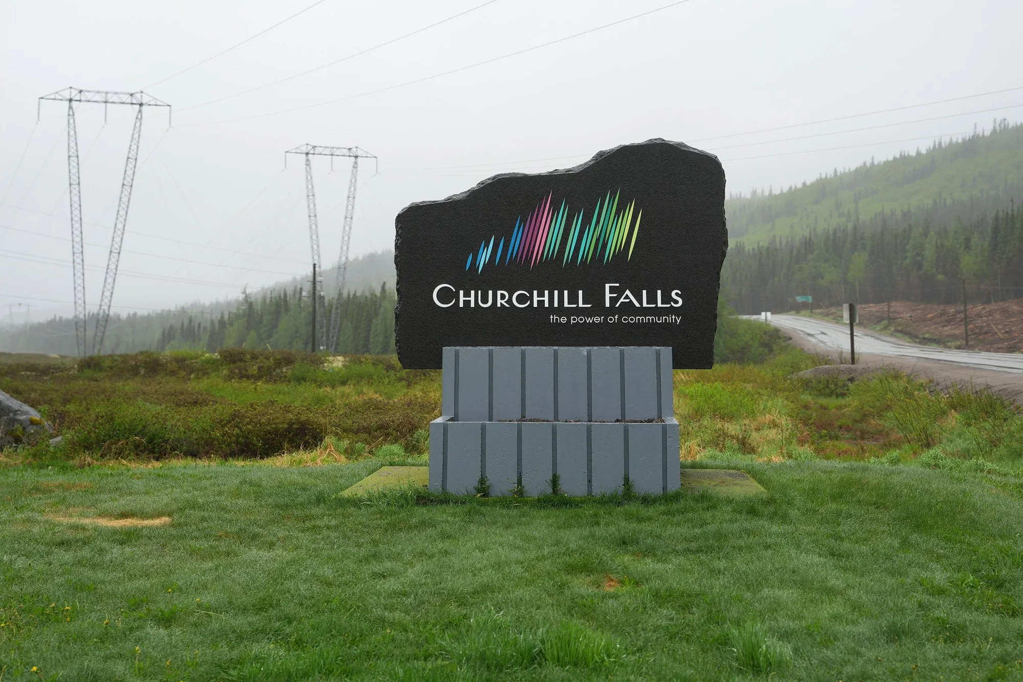 The Churchill Falls welcome sign beside the highway, with power lines behind