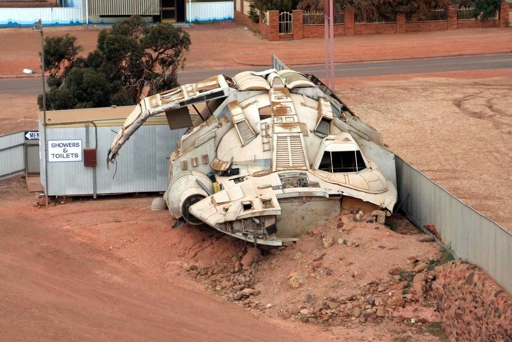 A white science-fiction spaceship prop sitting on red dirt beside a building in Coober Pedy