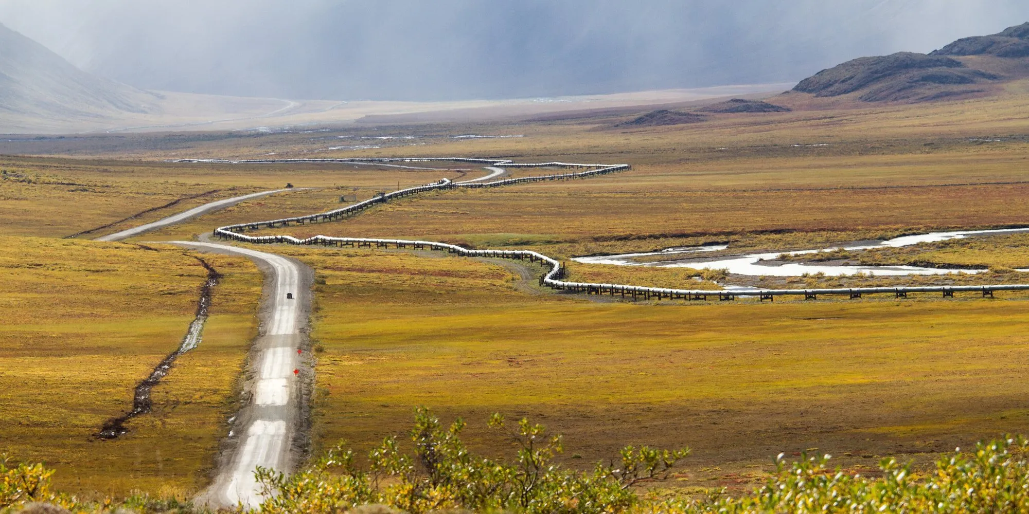 The Dalton Highway and the Trans-Alaska Pipeline running side by side across the autumn tundra