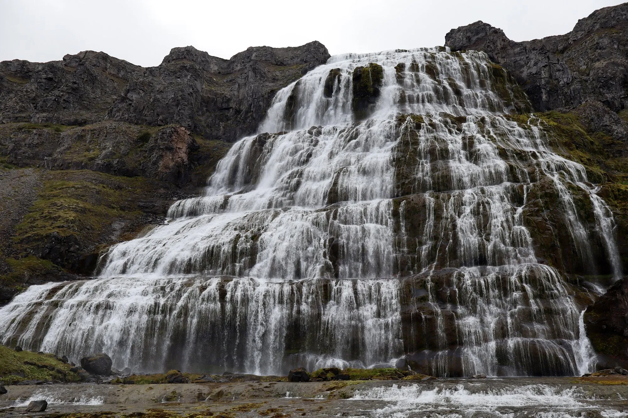Dynjandi waterfall spreading in a wide white veil down a stepped rock face