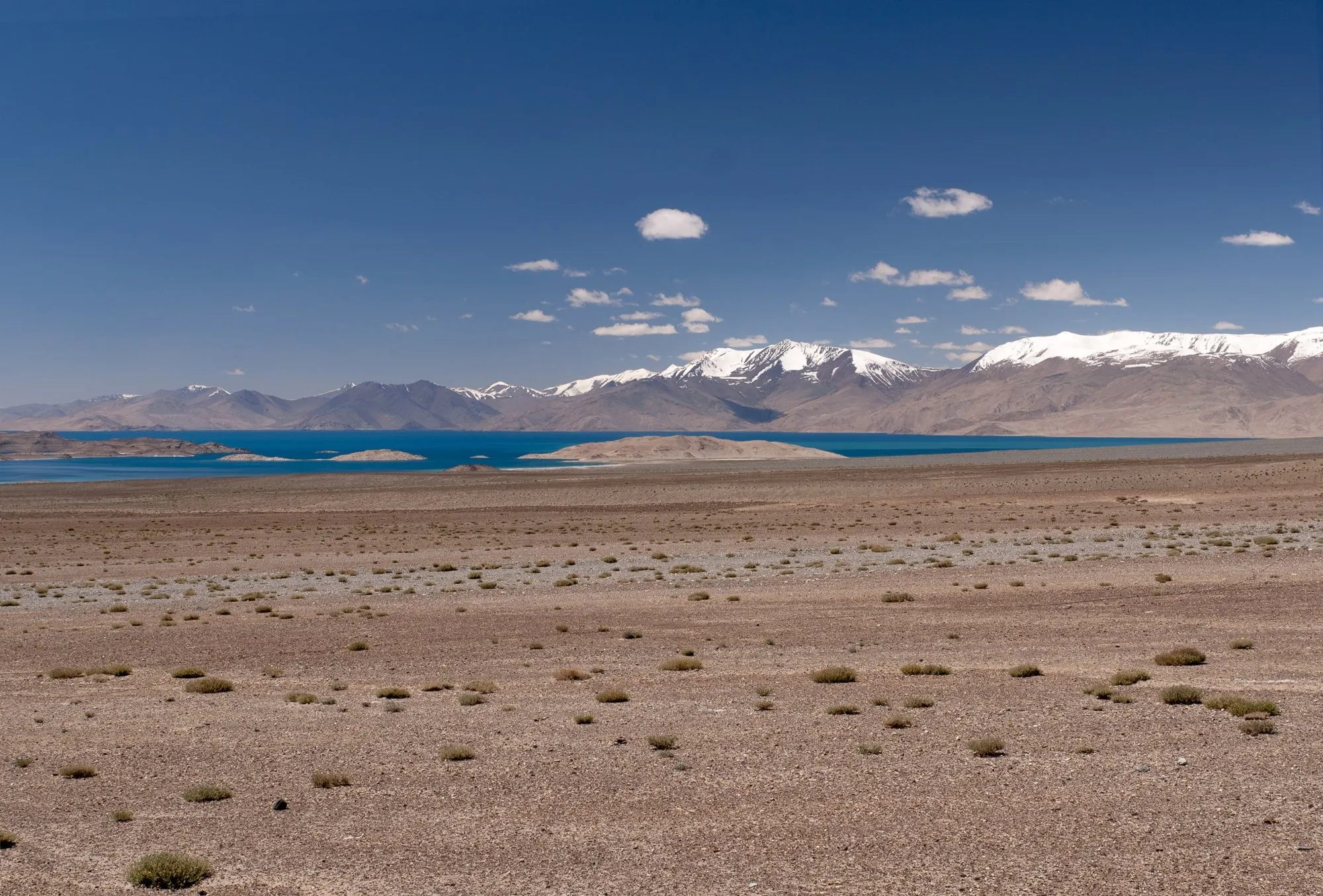 Karakul lake in the high Pamirs, with snow peaks beyond a stony plain
