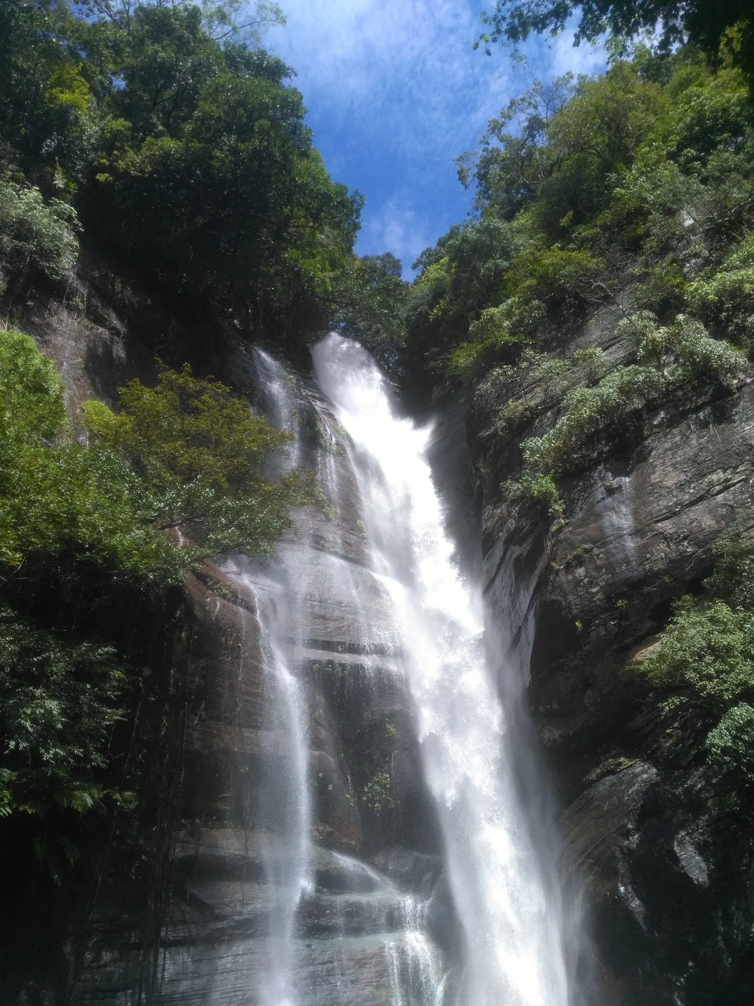 A waterfall dropping through a narrow, forested rock gorge