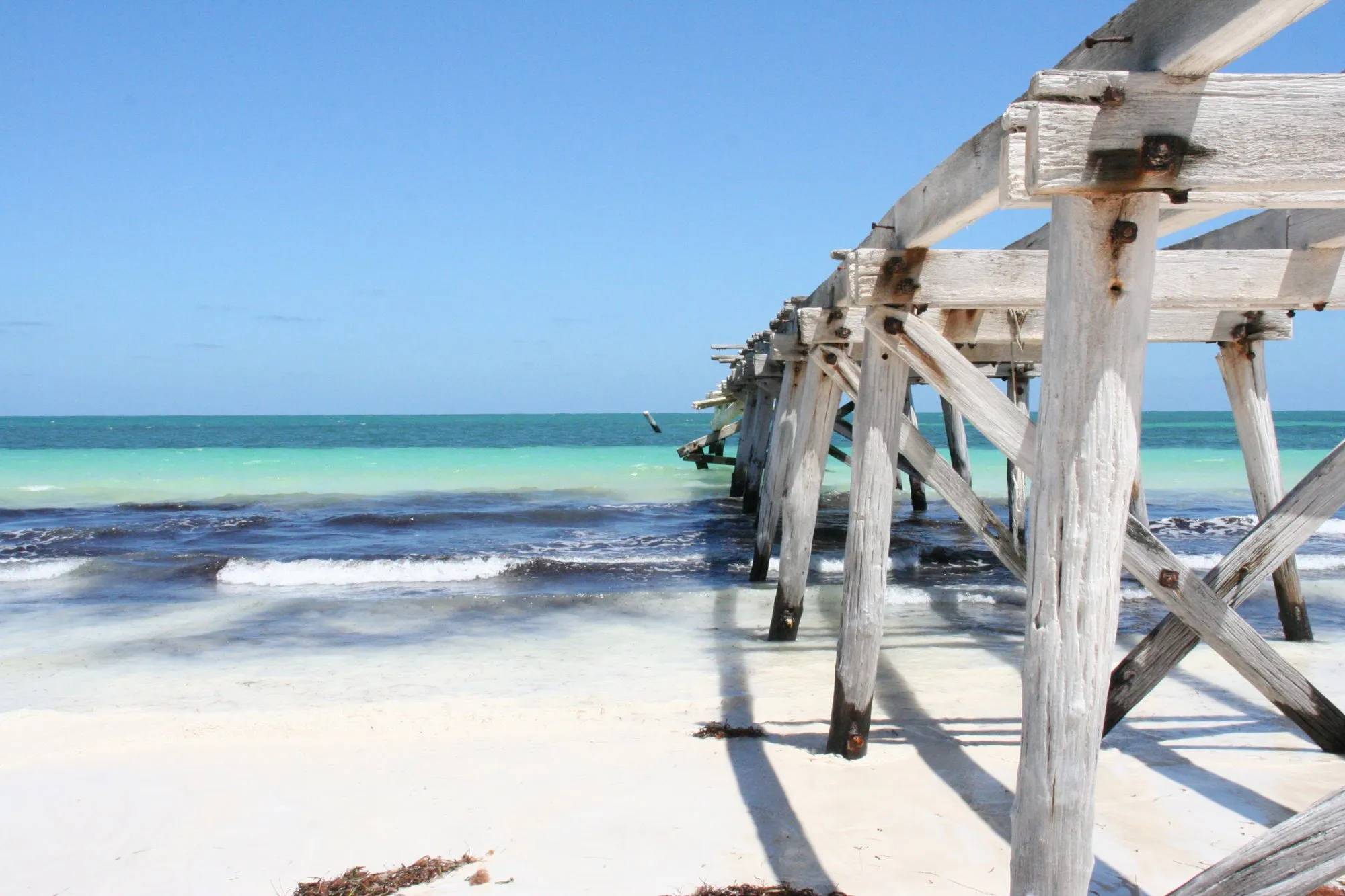 Weathered timber jetty over a white beach and turquoise water at Eucla