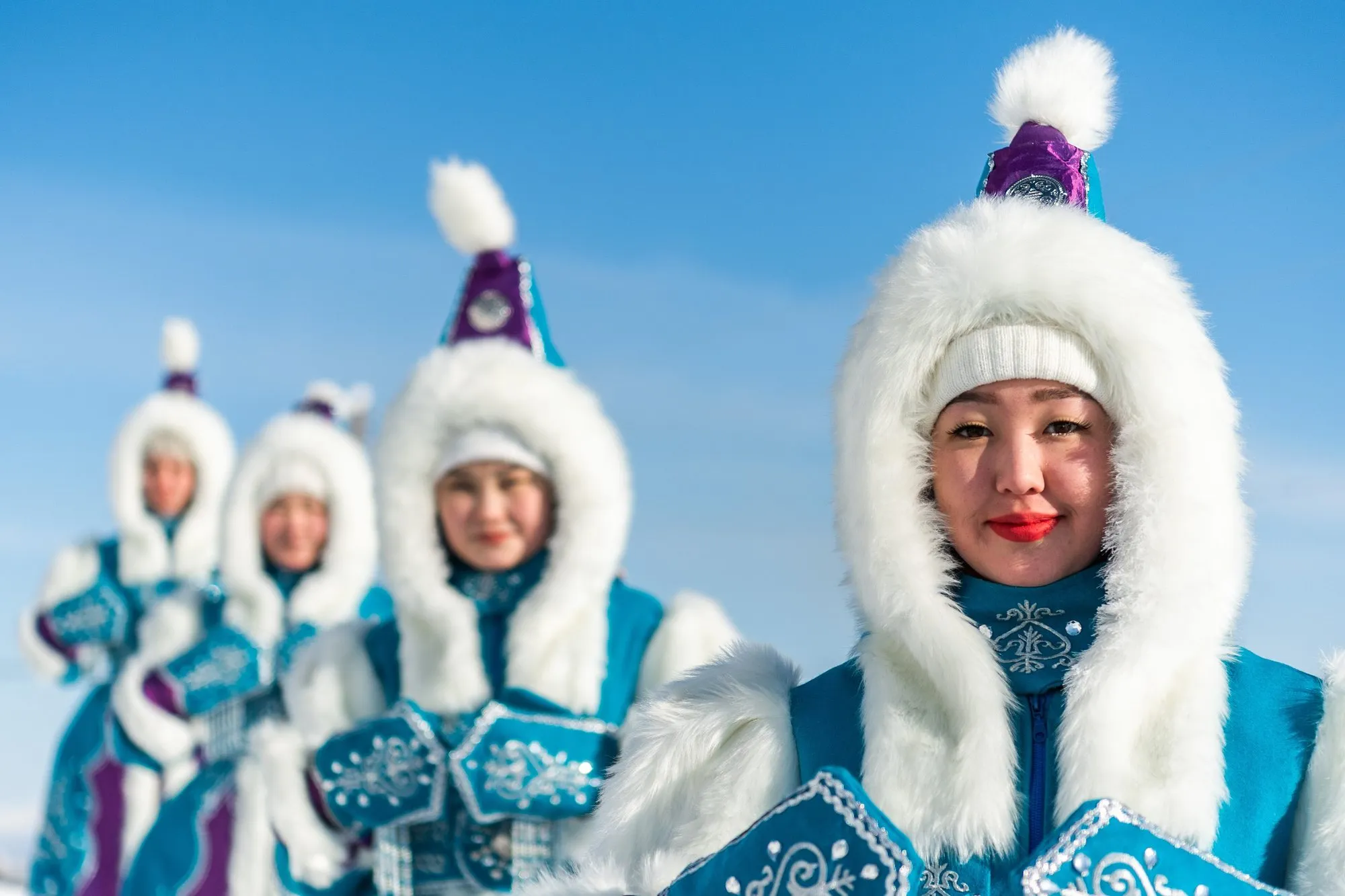 Women in traditional Yakut fur hats and blue embroidered coats in Oymyakon