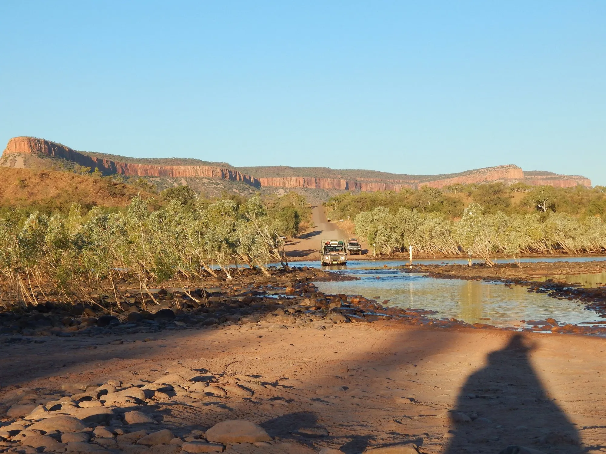 A 4WD crossing the shallow Pentecost River with the Cockburn Ranges behind