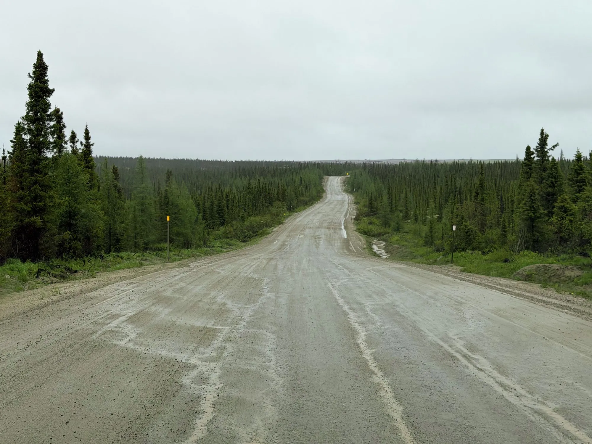 A gravel stretch of Quebec Route 389 running straight through dark spruce forest