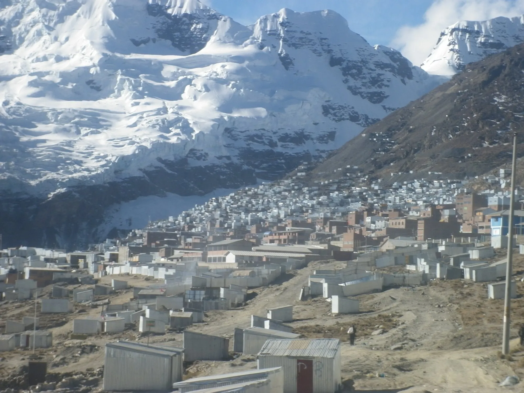 Rows of metal-roofed shacks spreading up a valley below the glacier of Mount Ananea at La Rinconada
