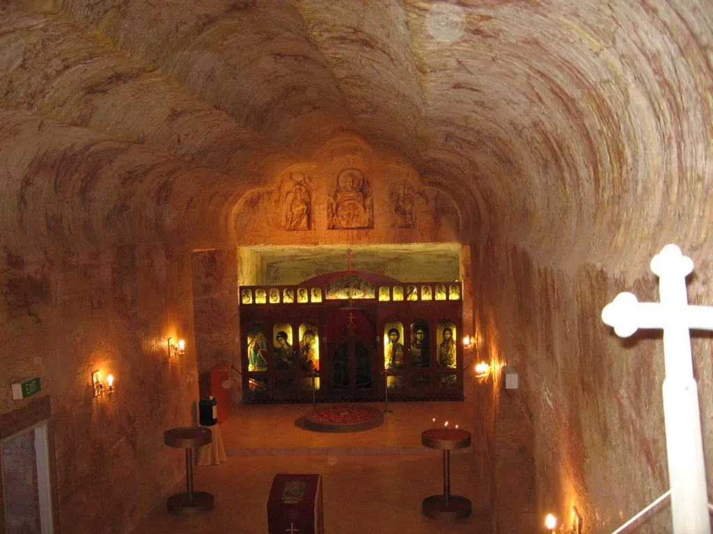 The candle-lit interior of the underground Serbian Orthodox church, with carved rock walls