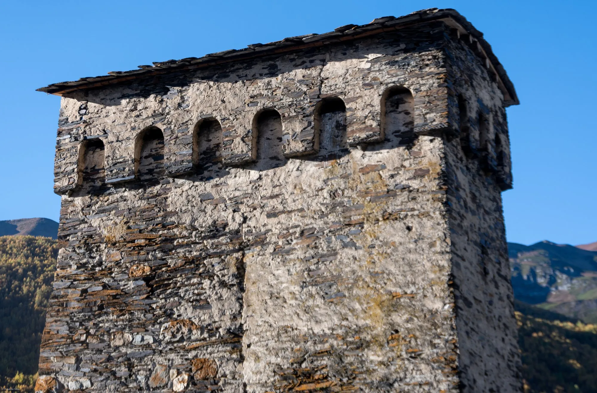 Close view of the top of a medieval stone defence tower with small arched openings