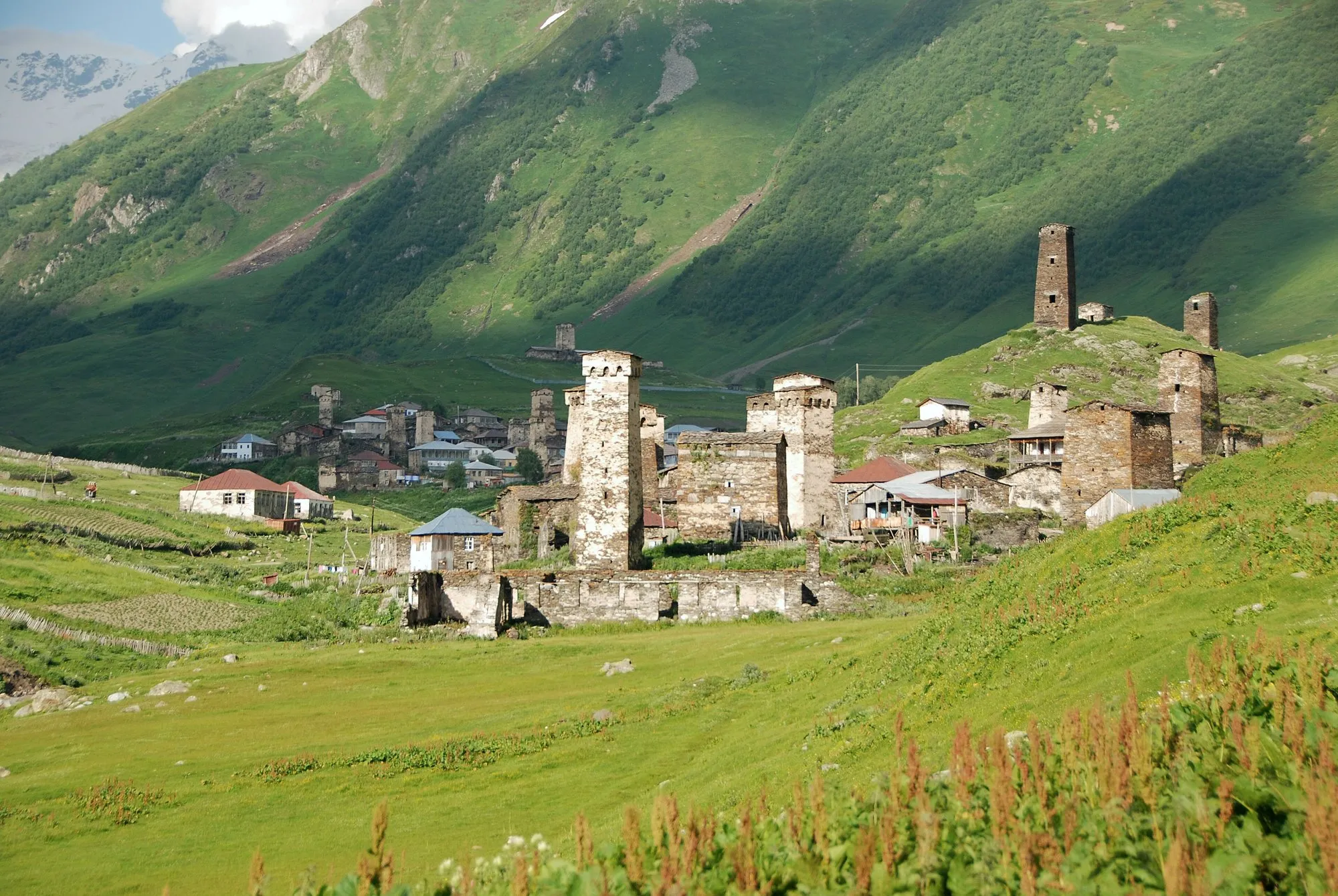 Stone Svan defence towers and houses on a green slope in Ushguli